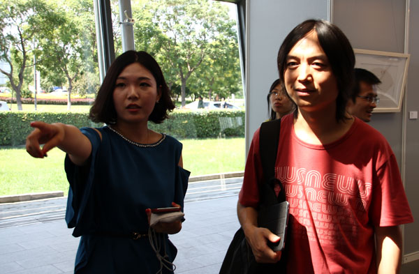 活动现场策展人胡珺涵（左）在向艺术学博士郝青松介绍作品