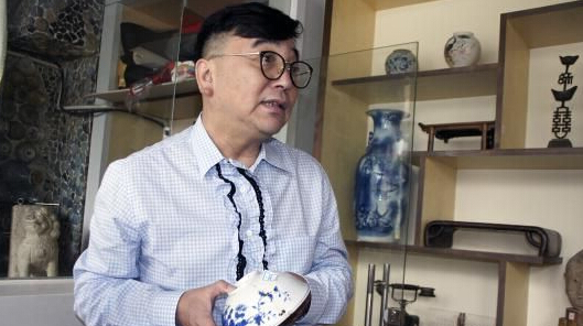 瓷房子主人张连志介绍自己收藏的古董。