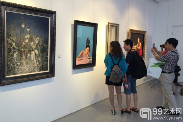 展览现场，观众正在欣赏写实油画作品