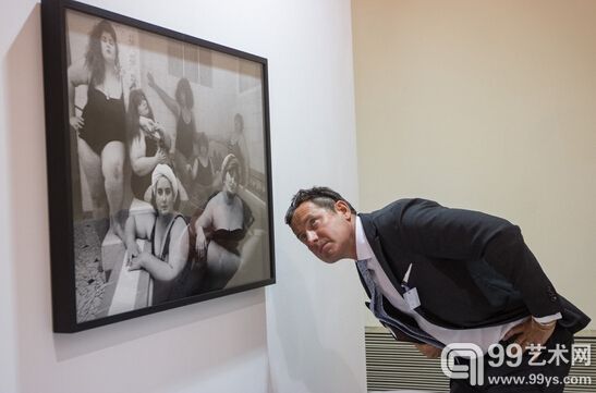 上海艺术影像博览会现场，画廊工作人员在细调墙上作品的位置。