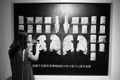 7月20日，在甘肃省博物馆，一位观众拍摄法国无偿归还我国的32件流失文物的展览图。              