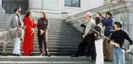 1998年春天，艺术家谷文达进行艺术表演【孔子日记】。谷文达着半袍子半礼服与毛驴壹路温哥华市中心并采访温哥华美术馆长和企业家们至诗大学美术馆展开幕式，他绕着市区走了一圈，并沿路与不同的人讨论他们对于全球问题的观点，图中，谷文达正在与温哥华美术馆主策展人黛娜奥·葛蒂思交流。从左至右：驴，训驴师，谷文达，黛娜奥·葛蒂思，汉克·布尔，陈大卫，胡杰明（照片来自谷文达工作室）