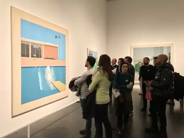 展览现场，人们正在欣赏大卫·霍克尼的另一幅“泳池”题材名作《更大的水花》（1967年），徐安琪拍摄。