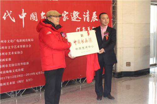 中国书画报社长何东向中国书画报中原艺术中心主任张新东授牌