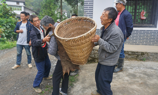 （当地村民热情的邀请松本秋則体验“背背篓”）