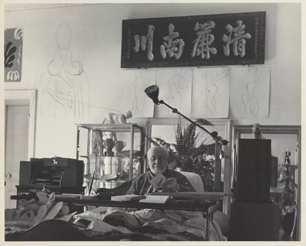 Matisse working on a cut-out under his Chinese calligraphy panel at Hôtel Régina, Nice, March 1951,Photograph by Philippe Halsman