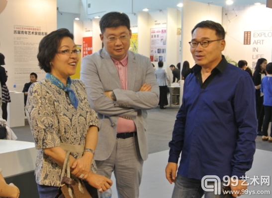 收藏家唐炬（右一）正在为朋友介绍他所收藏的艺术品