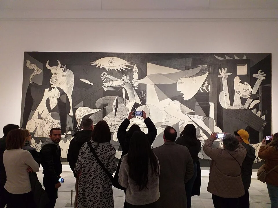 Photo of people taking pictures of &ldquo;Guernica.&rdquo; Image via Wikimedia Commons.